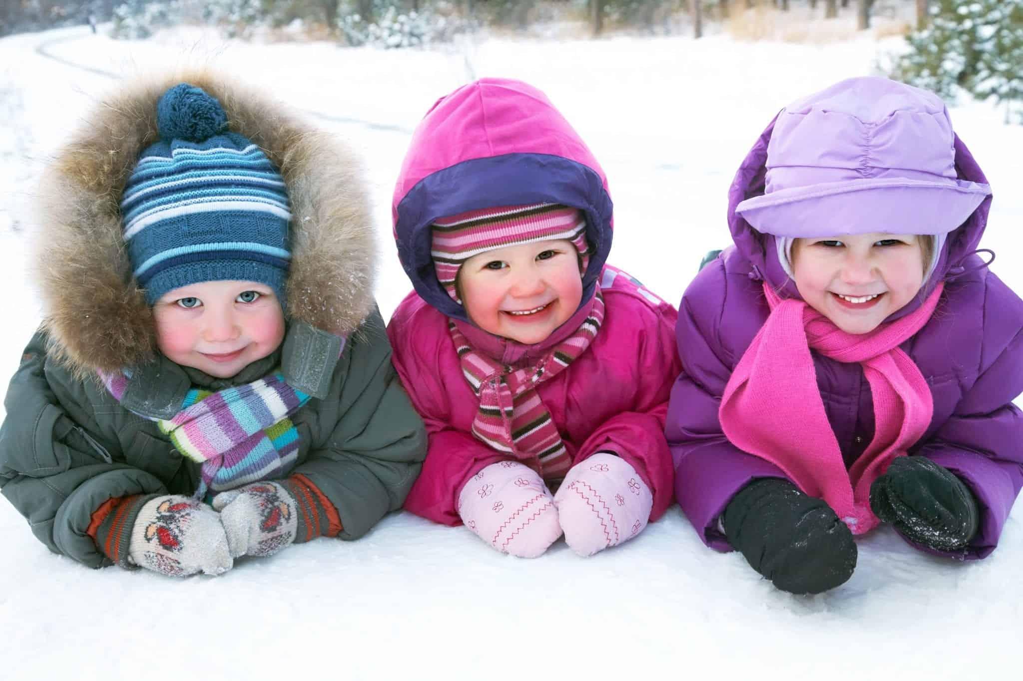 Three kids laying in the snow