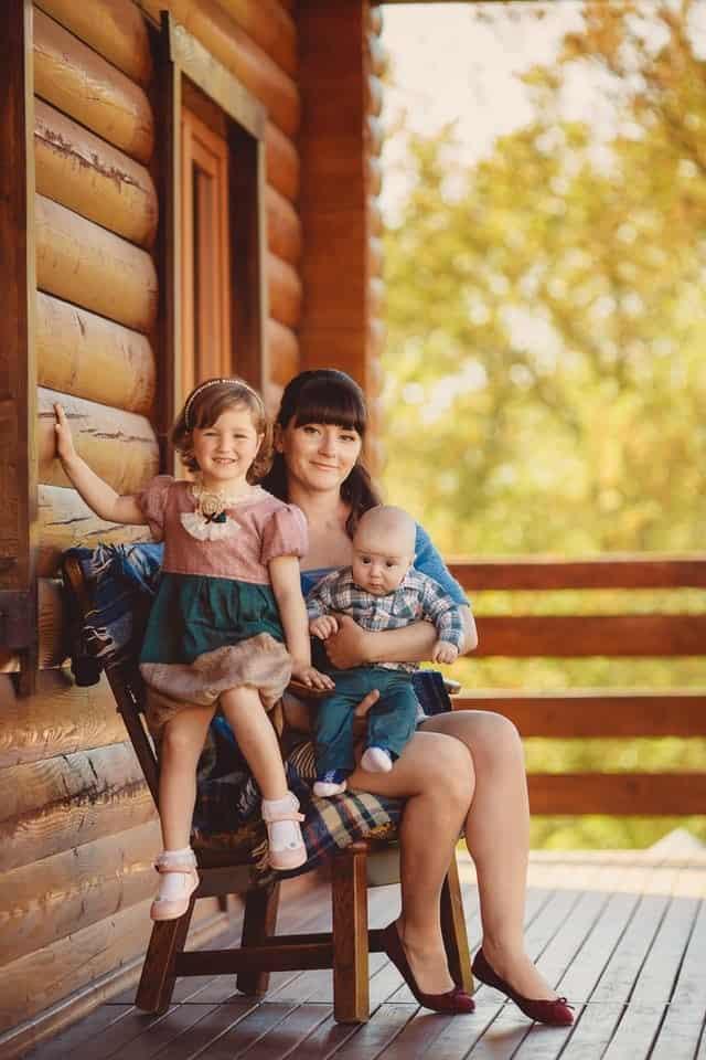 Mom and two children sitting outside cabin