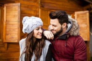 Young couple in winter clothing outside of their cabin.