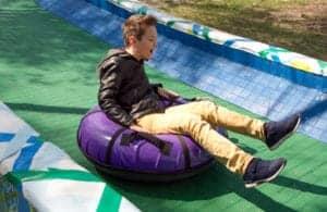 boy riding tube down a hill in summer